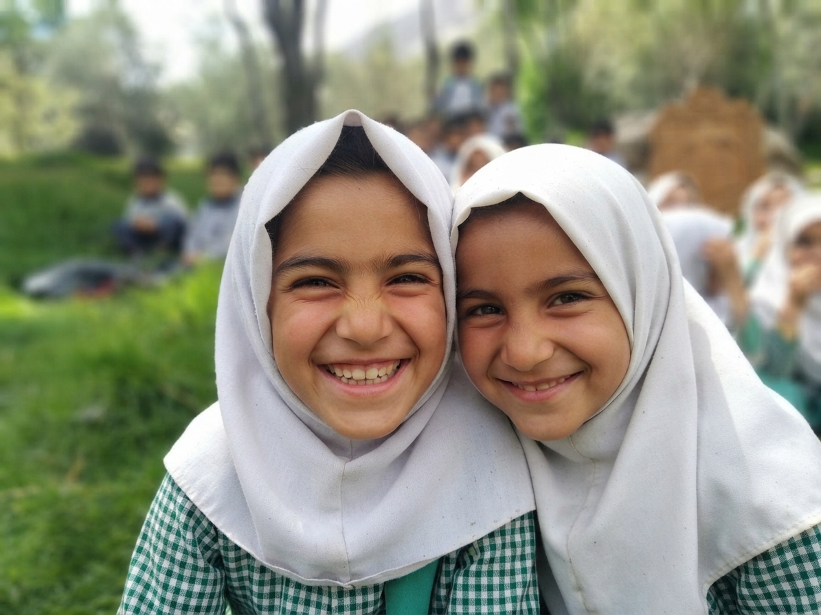 Two schoolgirls in white headscarves smiling at the camera