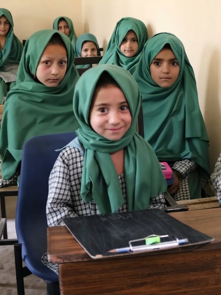 Schoolgirls in green headscarves at their desks in a Khadija Ibrahim Public School classroom
